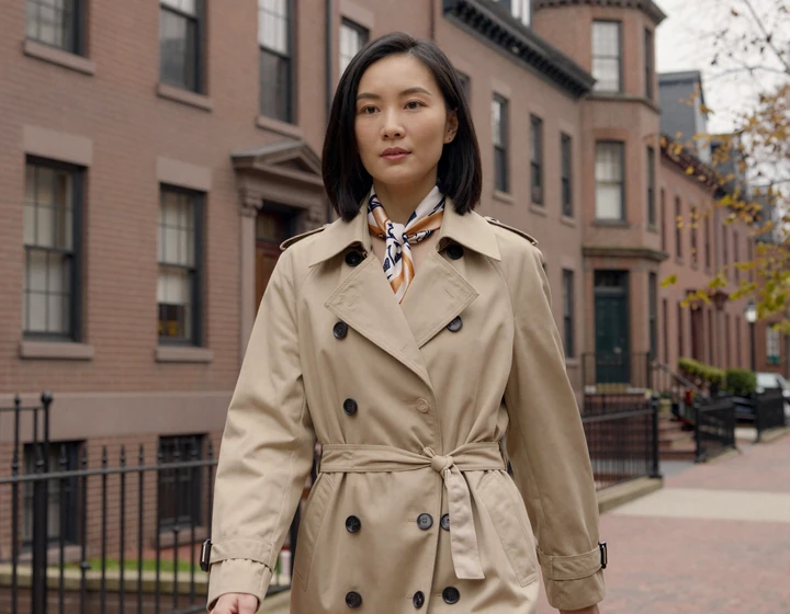 Stylish woman in a trench coat walking through Boston Back Bay brownstone neighborhood